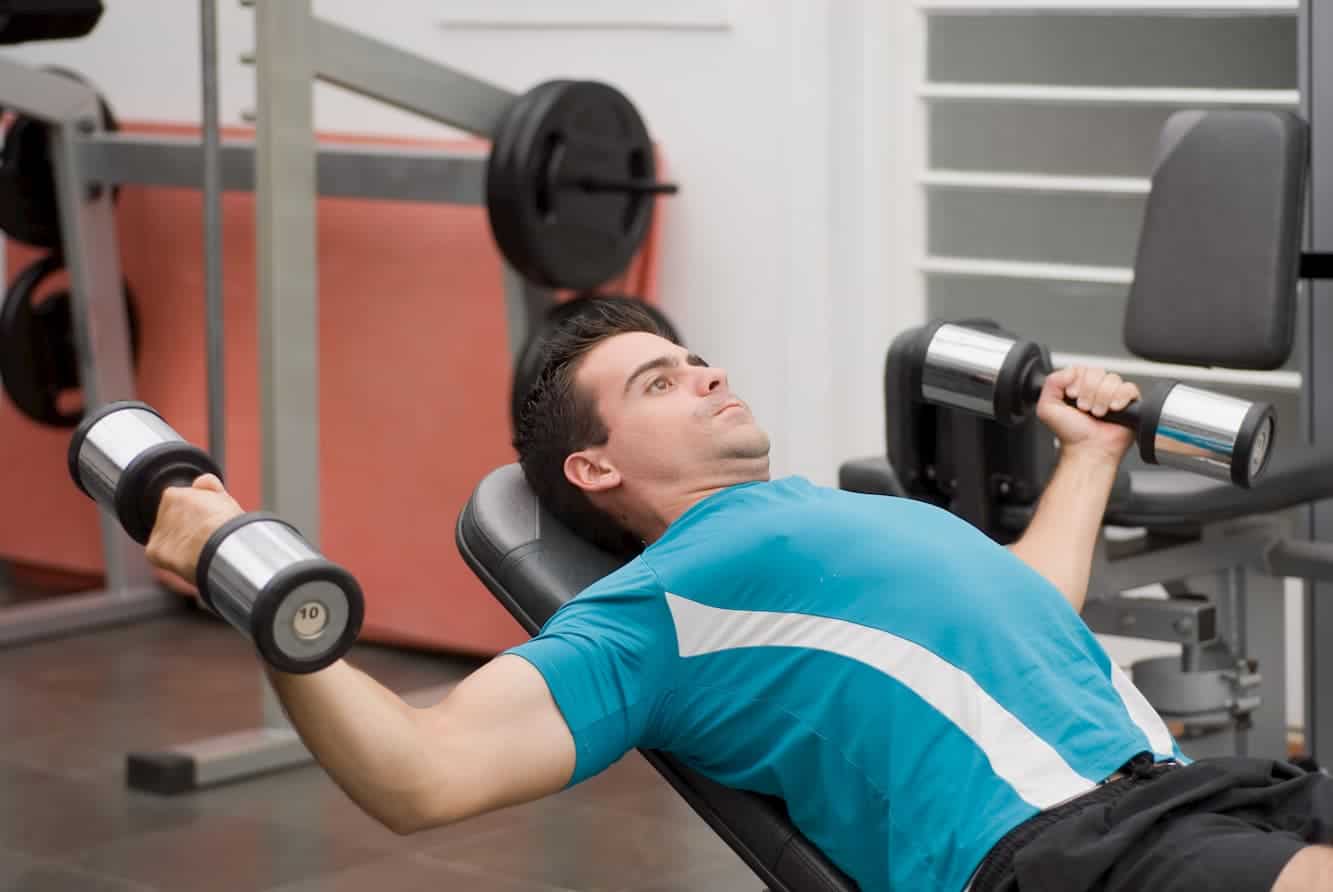 athletic man in the gym doing a chest press on a weight bench