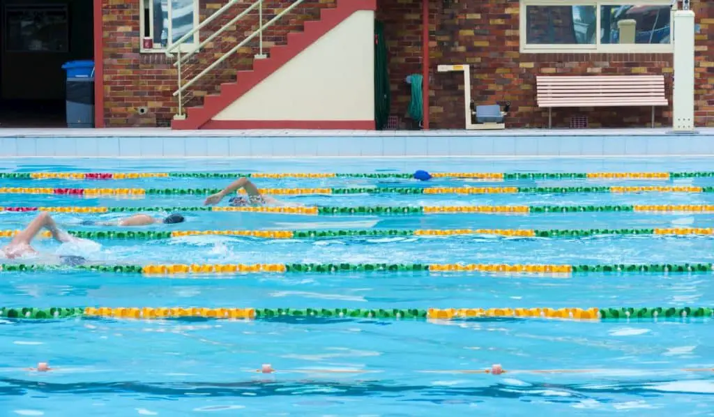 Four people swimming laps at an outdoor pool - How Long Do You Need to Swim to Get a Good Workout