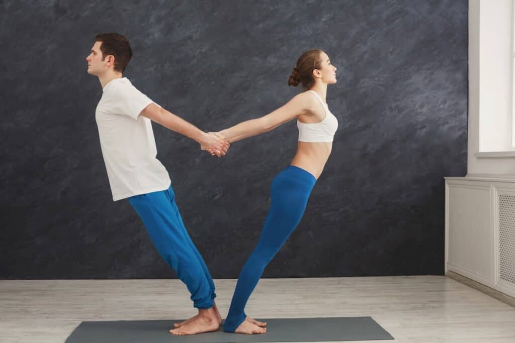 Couple training yoga in balance pose - what are the components of physical fitness