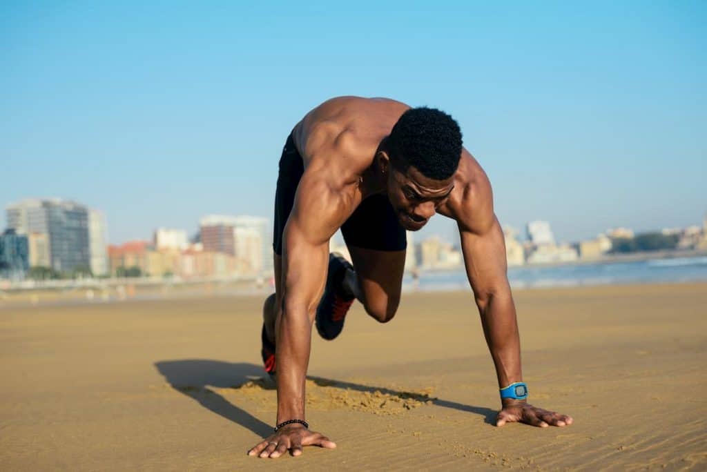 Mountain climbers exercise. Fit man warming up before running at the beach. Athlete on hiit cardio outdoor workout - How Many Times a Week Should I do HIIT Workouts