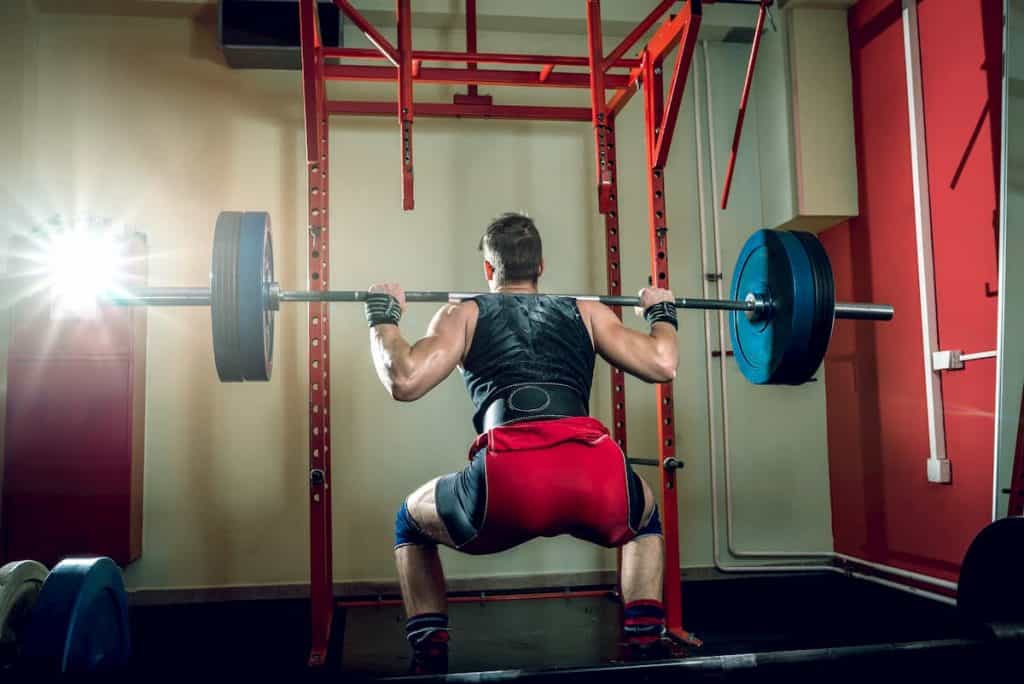 Young teenage man doing squats in indoor gym club - Is Running After Leg Day A Good Idea