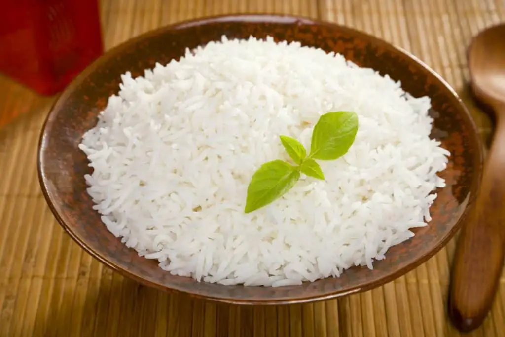 A bowl of perfectly cooked, plain Basmati rice, in an Asian style bowl, with a garnish of Thai Basil. - Is Basmati Rice Healthy For Weight Loss