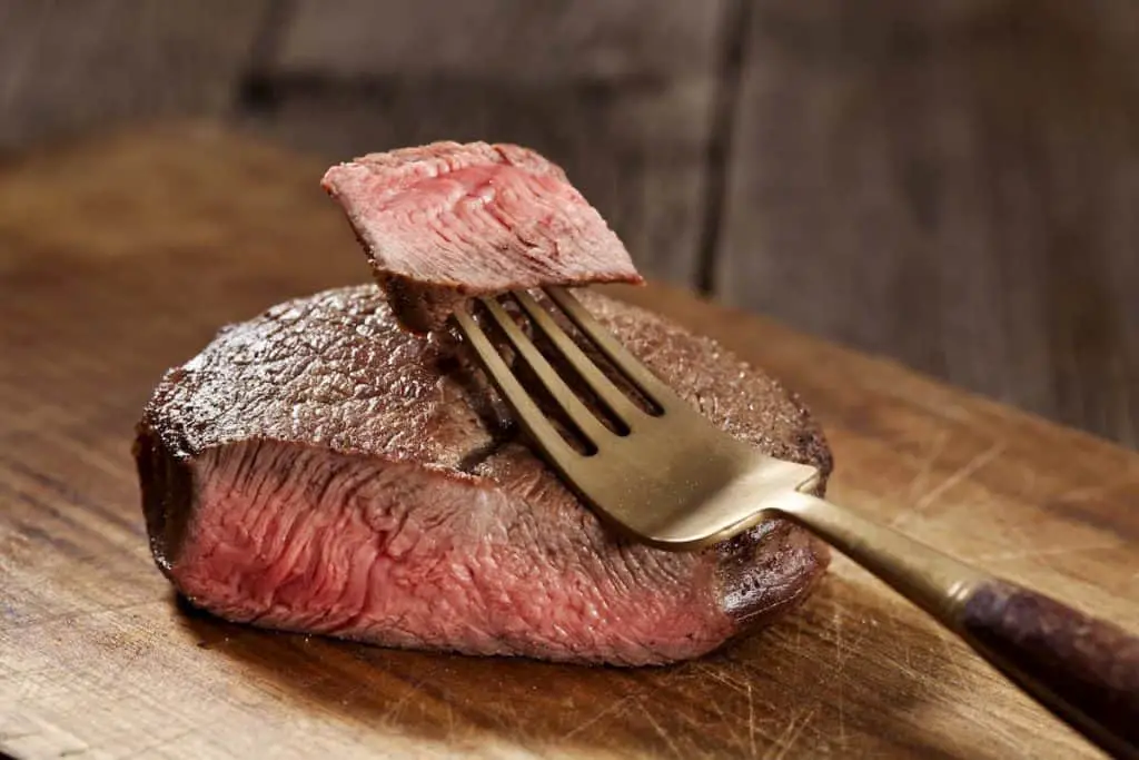 Beef steak cooked to medium rare on wooden background - What is the Carnivore Diet Plan