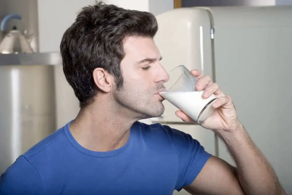 Man drinking milk in the kitchen leads me to wonder is Milk Good After Workout?