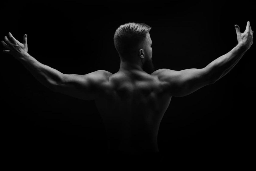 Muscular man stands with his back and spread his arms to the side - what is considered broad shoulders