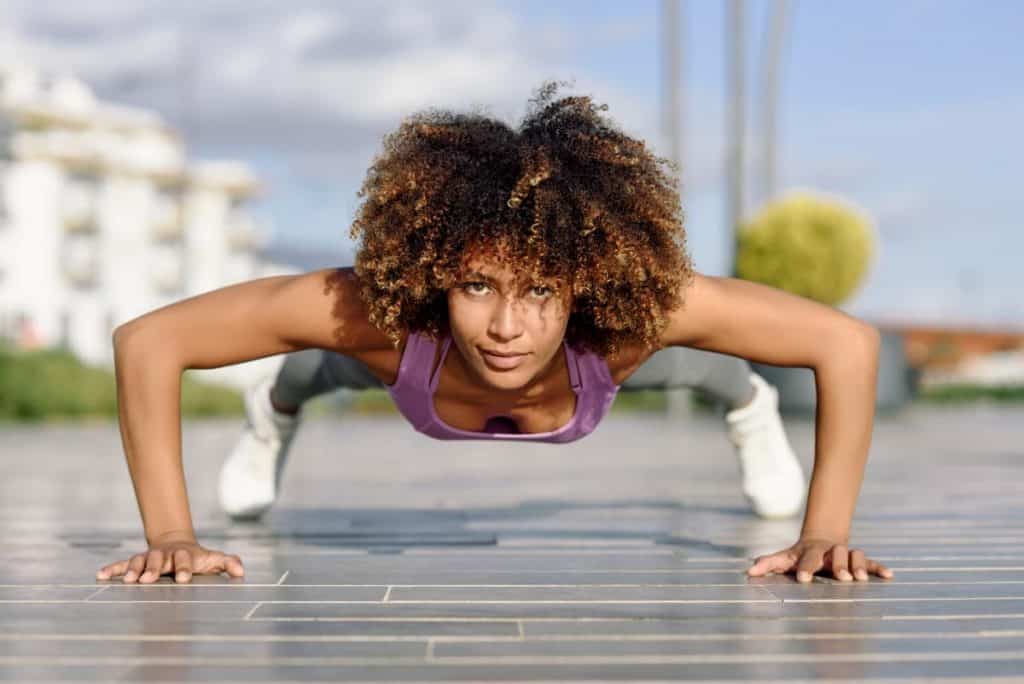 Fit woman doing pushups on brick - Do Push Ups Help Build Muscle