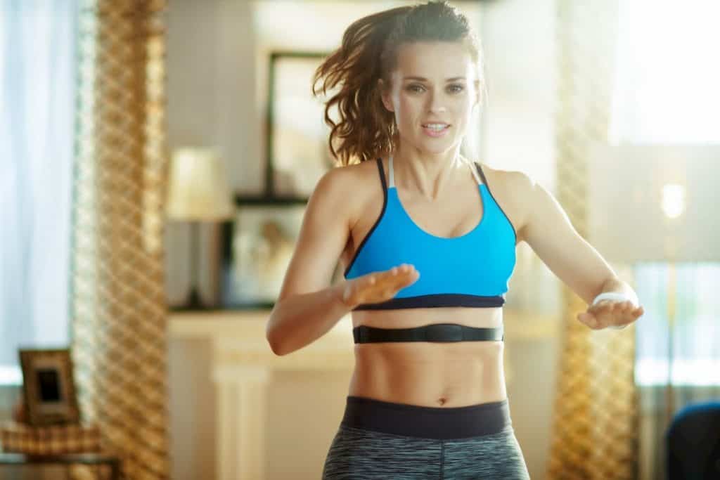 woman in sport clothes at modern home workout and using heart rate monitor - how effective is hiit for weight loss