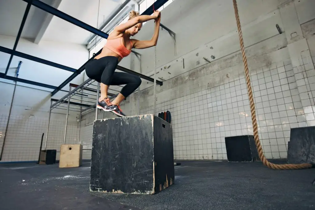 Fit young woman box jumping at a crossfit style gym