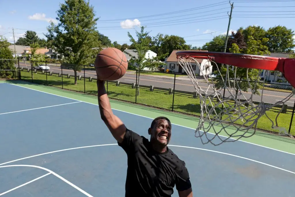 A young basketball player dunking a basketball as seen from rim level.