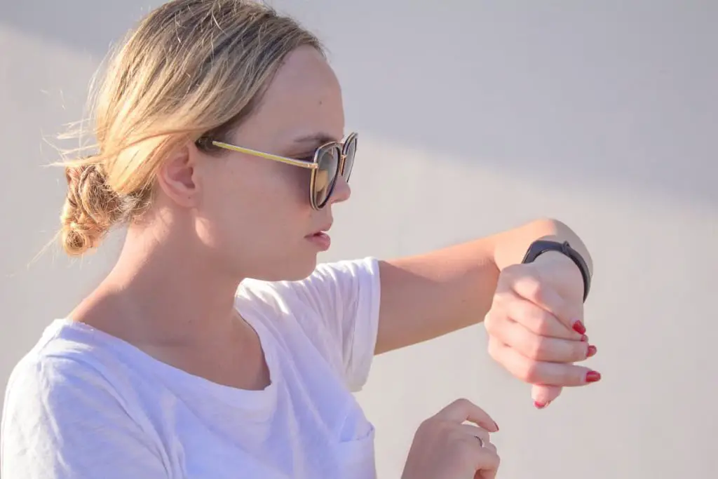 Girl is switching on her Fitbit bracelet tracker before training.